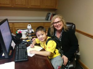 Patrick sitting at Tina's desk in her office