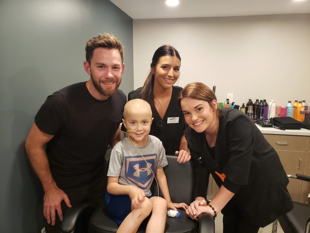 Jax in the chair at the House salon surrounded by students and a teacher from Capitol School of Hairstyling and Esthetics