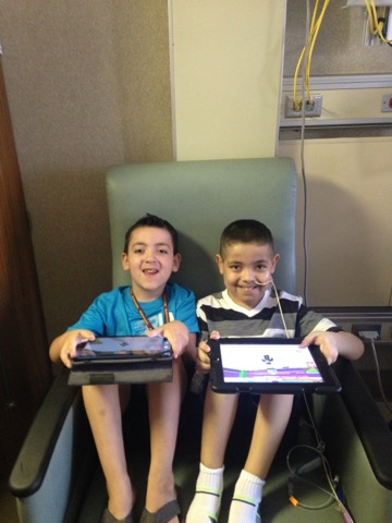 Daniel and Jonathan sitting in the same chair, holding their own tablets