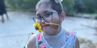 Neely stands holding a yellow flower