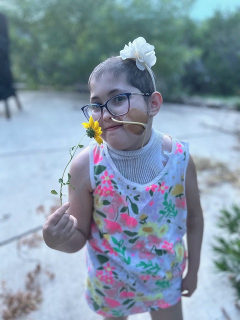 Neely stands holding a yellow flower