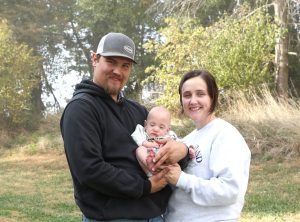 Couy and Taylor Johnson stand holding baby Thayne