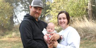 Couy and Taylor Johnson stand holding baby Thayne